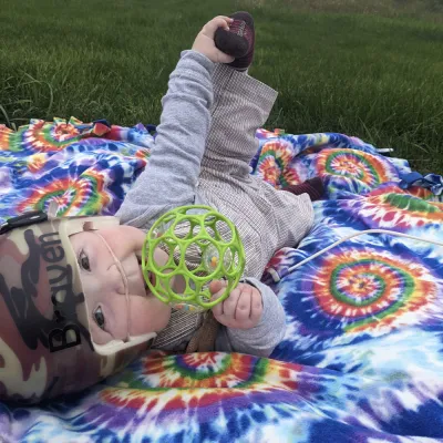 Baby wearing helmet outside on blanket