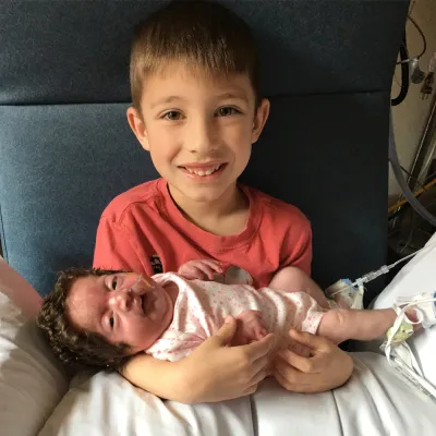 New brother holding baby sister at the hospital