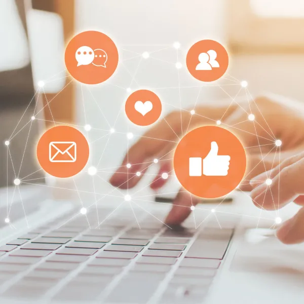 Photo of hands at computer with orange social icons in forefront