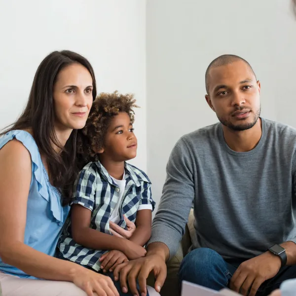 Parents with child on a couch listening to someone else speak