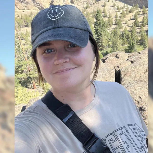 selfie of a young woman smiling with mountains in the background