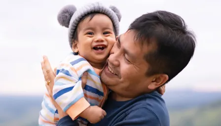 Smiling an holding a smiling baby cheek to cheek