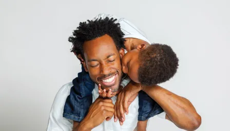 Son on dads shoulders kissing his cheek