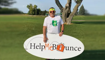 Man outside holding Help Me Bounce sign