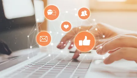 Photo of hands at computer with orange social icons in forefront