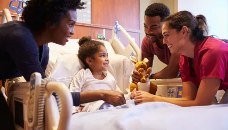Girl in hospital bed with parents and doctor by her side