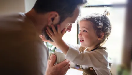 Girl holding dads face in front of window