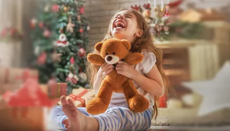 little girl holding a teddy bear with huge smile 