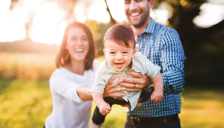 Smiling parents holding a smiling child outside