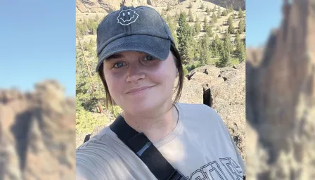 selfie of a young woman smiling with mountains in the background 